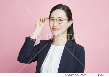 A smiling businesswoman touches her glasses. A smiling businesswoman touches her glasses. 138845660