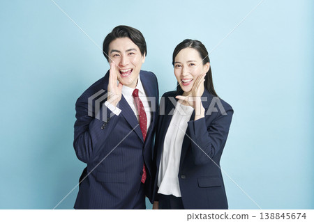 A man and a woman in suits call out with smiles. 138845674