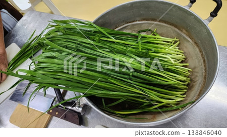 Fresh Green Garlic Chives in a Large Metal Pot for Cooking Asian Cuisine Fresh Green Garlic Chives in a Large Metal Pot for Cooking Asian Cuisine 138846040