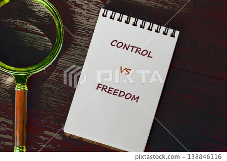 A white spiral-bound notebook displays the words Control versus Freedom A white spiral-bound notebook displays the words Control versus Freedom 138846116