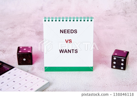 White notepad displays NEEDS VS WANTS text on a pink surface White notepad displays NEEDS VS WANTS text on a pink surface 138846118