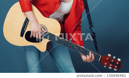 Musician in red studded jacket playing acoustic guitar, cropped view Musician in red studded jacket playing acoustic guitar, cropped view 138846462