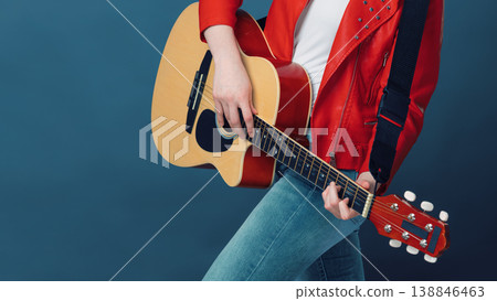 Musician in a red jacket playing an acoustic guitar against a blue background Musician in a red jacket playing an acoustic guitar against a blue background 138846463