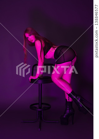 Young woman dressed in lingerie and stripper platform heels stands leaning on bar stool Young woman dressed in lingerie and stripper platform heels stands leaning on bar stool 138846577