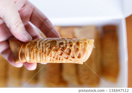 Hand holding pancake roll filled with assorted filling. 138847512