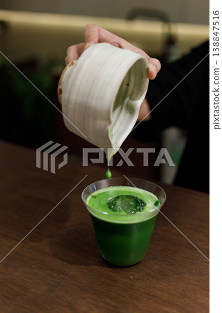 fresh matcha tea, green tea pouring on a glass on wooden table. 138847516