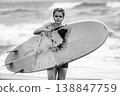 Monochrome portrait of serious young woman with short hair holding surfboard on beach 138847759