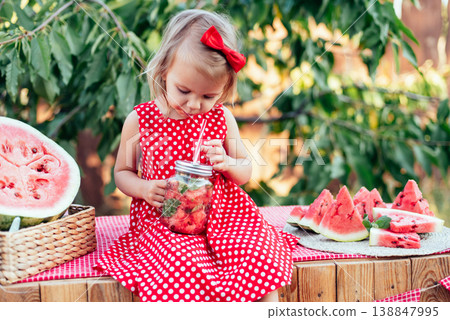 Cute child eats ripe juicy watermelon at summertime. Child, baby, healthy food snack for children. Adorable little girl trying to sell lemonade. Watermelon lemonade with ice and mint Cute child eats ripe juicy watermelon at summertime. Child, baby, healthy food snack for children. Adorable little girl trying to sell lemonade. Watermelon lemonade with ice and mint 138847995