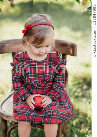 Child picking apples on farm in autumn. Little girl playing in apple tree orchard. Healthy nutrition. Cute little girl eating red delicious apple. Apple picking. Child picking apples on farm in autumn. Little girl playing in apple tree orchard. Healthy nutrition. Cute little girl eating red delicious apple. Apple picking. 138847999