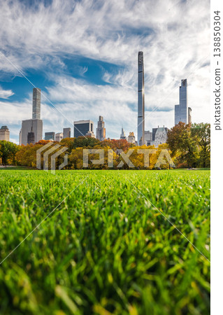 Low angle view of green grass field in Central Park with Manhattan skyline and autumn trees under dramatic clouds in New York City USA Low angle view of green grass field in Central Park with Manhattan skyline and autumn trees under dramatic clouds in New York City USA 138850304