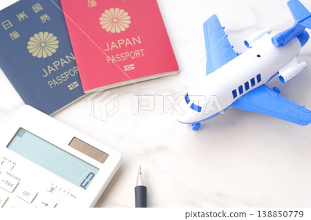 一張照片,照片中的人正在計劃一次海外旅行,照片裡有計算器、飛機和護照(一本有效期為 10 年的紅色護照和一本有效期為 5 年的深藍色護照)。 一張照片,照片中的人正在計劃一次海外旅行,照片裡有計算器、飛機和護照(一本有效期為 10 年的紅色護照和一本有效期為 5 年的深藍色護照)。 138850779