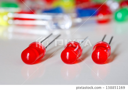 Red LED diodes aligned on white background with colorful blurred electronics Red LED diodes aligned on white background with colorful blurred electronics 138851169