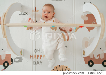 Cute baby resting on play mat under activity gym toys. Concept of parenting, infant learning and childhood playtime. 138851223