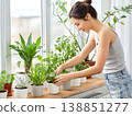 A woman carefully tending to her indoor plants. 138851277