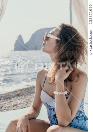 Woman beach vacation sitting in a cabana overlooking the sea and rocky cliffs while enjoying the sunlight Woman beach vacation sitting in a cabana overlooking the sea and rocky cliffs while enjoying the sunlight 138851636