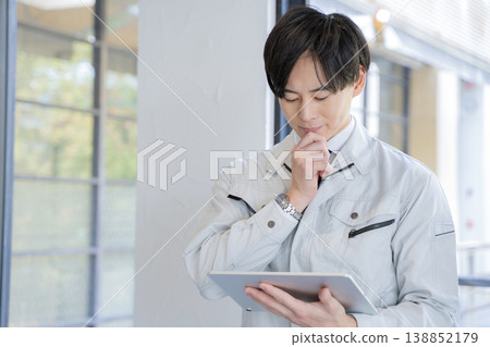 A male worker thinking with a tablet in his hand. A male worker thinking with a tablet in his hand. 138852179