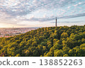 A stunning sunrise lights up the sky over the Petrin Lookout Tower in Prague. Nestled on a hill, the tower overlooks lush greenery and the city skyline, creating a serene atmosphere. 138852263