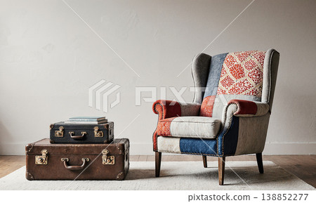 Armchair, suitcase, interior, a colorful patchwork wingback chair sits beside stacked vintage trunks in a minimalist room with copy space 138852277