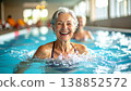 Happy senior woman laughing while doing water aerobics in swimming pool. Healthy elderly lifestyle, fitness for seniors, and active retirement concept with water splashes and bright sunlight 138852572