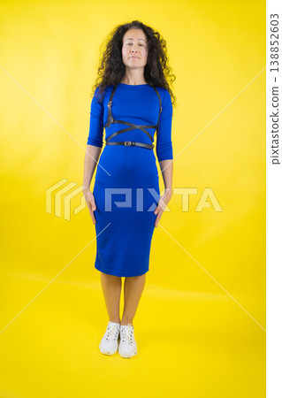 Woman wearing blue dress and chest harness standing casually Woman wearing blue dress and chest harness standing casually 138852603