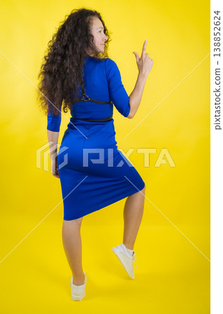 Woman pointing finger up indicating direction on yellow 138852624