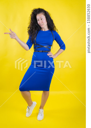Woman pointing finger presenting information against yellow background Woman pointing finger presenting information against yellow background 138852630