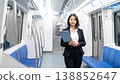 confident Asian businesswoman holding clipboard standing in subway train. Professional female employee commuter in black suit for business travel, career, and leadership concept 138852647