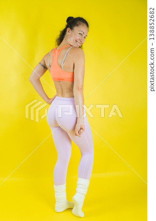 Woman posing in activewear against yellow background 138852682