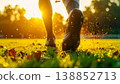 soccer player feet running on green grass field at stadium during sunset. Football boots action with mud splashes, golden sun flare, and blurred background for sports competition 138852713