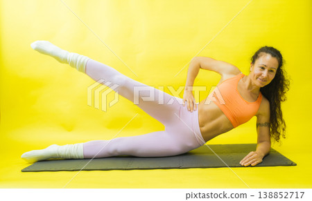 Woman training body with side leg raise exercise Woman training body with side leg raise exercise 138852717