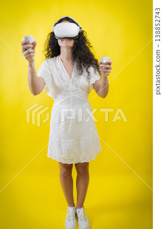 Woman experiencing virtual reality wearing headset and controllers Woman experiencing virtual reality wearing headset and controllers 138852743
