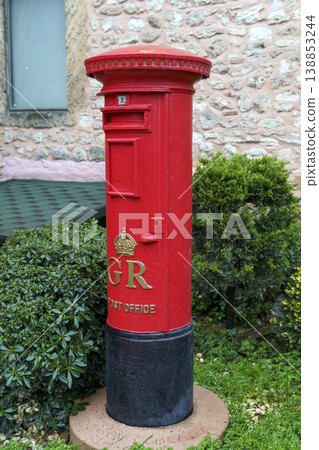Red British Post Box Installed Outdoors Near Stone Wall 138853244