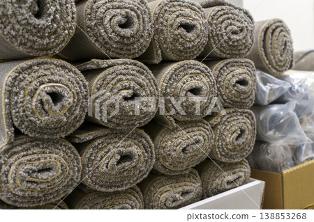 Industrial carpet production and storage with large rolls of textile flooring. Manufacturing process of various synthetic carpets in a warehouse or factory facility. 138853268