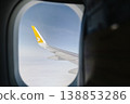 Flying airplane over the clouds. Airplane wing against a clear blue sky background during a commercial flight, conceptual travel and transportation photography. 138853286