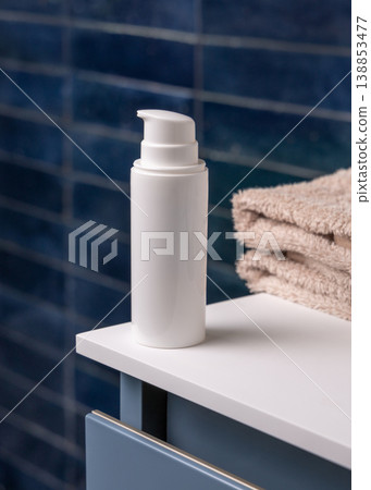 White pump cosmetic bottle near beige towel in dark blue bathroom close up, cosmetic mockup White pump cosmetic bottle near beige towel in dark blue bathroom close up, cosmetic mockup 138853477