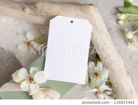 Blank vertical gift tag mockup with white spring flowers and driftwood on light stone, product tag Blank vertical gift tag mockup with white spring flowers and driftwood on light stone, product tag 138853483