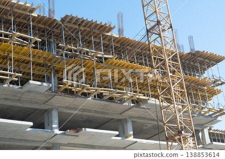Construction of a multi-story building progresses under clear blue skies, showcasing the intricate framework and scaffolding necessary for modern architecture Construction of a multi-story building progresses under clear blue skies, showcasing the intricate framework and scaffolding necessary for modern architecture 138853614