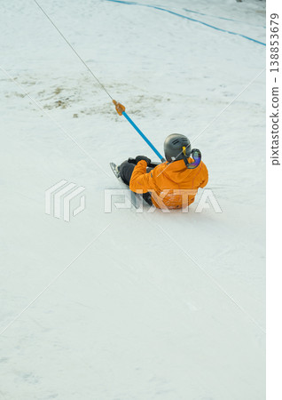 Experience the excitement of a thrilling winter adventure, where a lone sledder gracefully glides down a snowy slope, all beneath a clear, breathtaking blue sky 138853679