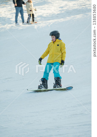 Snowboarder glides smoothly down a winter slope with joyful focus while friends enjoy the snowy landscape in the background during a sunny afternoon of winter fun Snowboarder glides smoothly down a winter slope with joyful focus while friends enjoy the snowy landscape in the background during a sunny afternoon of winter fun 138853680