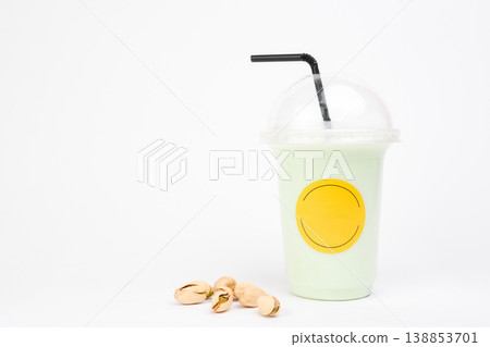 Fresh mint milkshake from served in a clear cup with a black straw alongside delightful pistachio nuts in a cozy setting 138853701