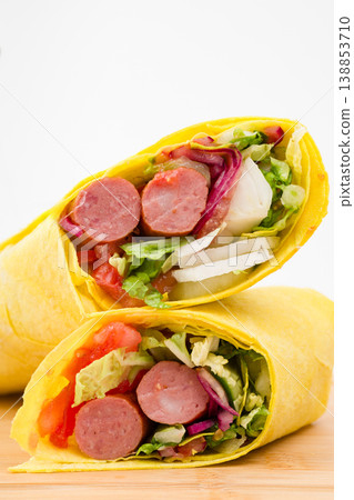 Delicious and colorful wrap filled with savory sausages, fresh vegetables, and vibrant greens, perfect for a quick meal or picnic delight any time of day Delicious and colorful wrap filled with savory sausages, fresh vegetables, and vibrant greens, perfect for a quick meal or picnic delight any time of day 138853710