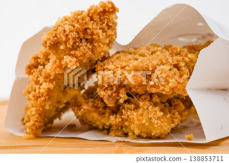 Crispy golden fried chicken pieces in a white takeout box on a wooden surface ready to be enjoyed during a casual meal at home or on the go Crispy golden fried chicken pieces in a white takeout box on a wooden surface ready to be enjoyed during a casual meal at home or on the go 138853711