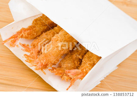 Crispy golden shrimp tempura served in a white paper bag on a wooden table, inviting deliciousness for seafood lovers at lunchtime Crispy golden shrimp tempura served in a white paper bag on a wooden table, inviting deliciousness for seafood lovers at lunchtime 138853712