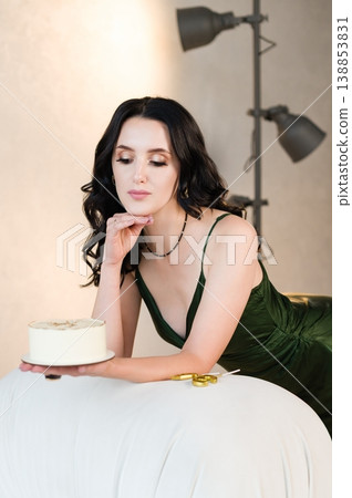 Woman in green dress admiring a cake. Woman in green dress admiring a cake. 138853831