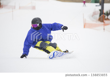 A young woman carving on a snowboard 138853855