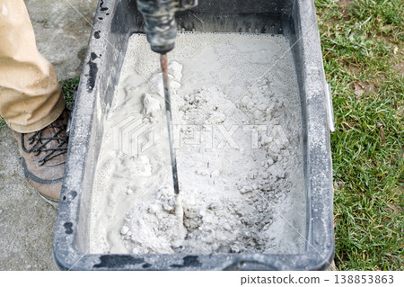 Mixing cement in a container for construction work at a job site on a clear day Mixing cement in a container for construction work at a job site on a clear day 138853863
