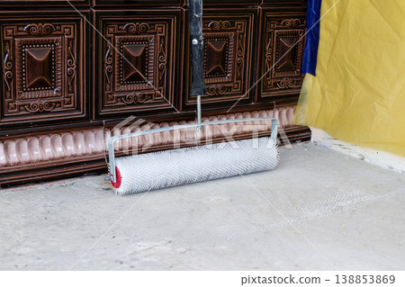 Roller tool placed on the floor near decorative wall and colorful fabric in a building space during a renovation project Roller tool placed on the floor near decorative wall and colorful fabric in a building space during a renovation project 138853869