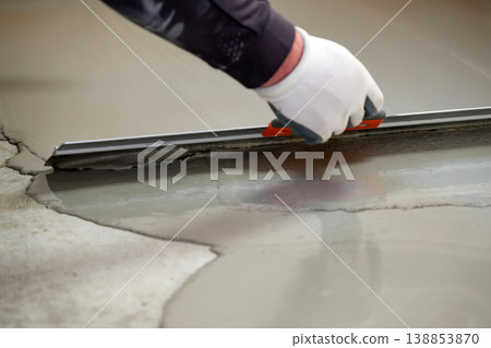 Worker applies cement to smooth the surface self-leveling floor in a construction area during daytime 138853870