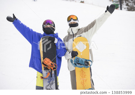 一男一女手持滑雪板站在滑雪道上。 138853999