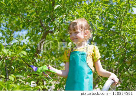 Child gardening outdoors with tools in green garden 138854591